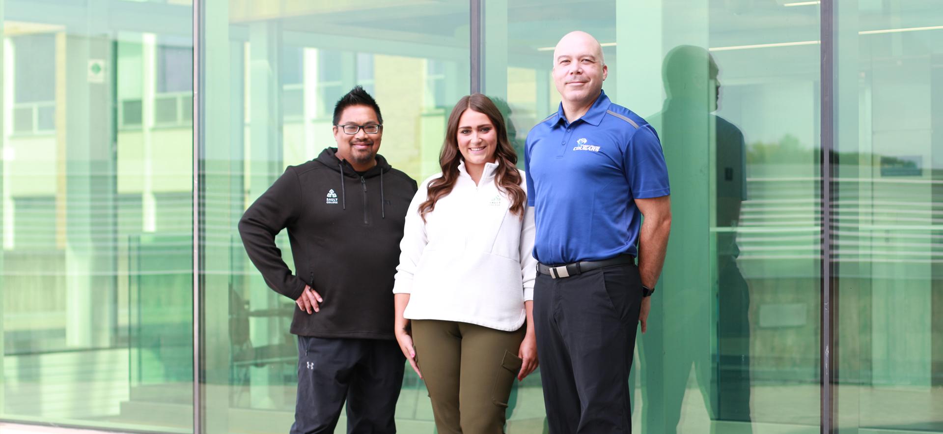 Three of our recruiters posed in front of wall of windows