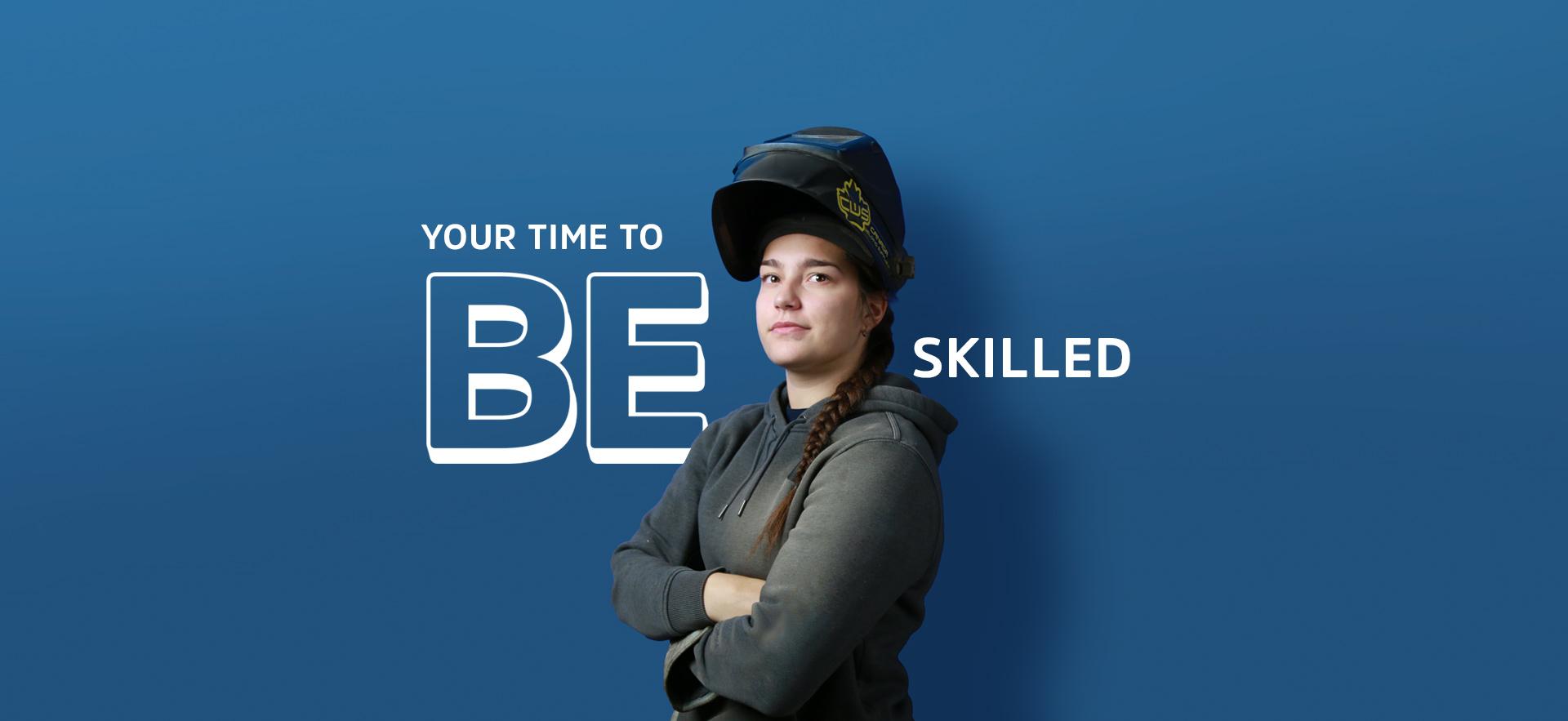 Skilled Trades student wearing a welding mask lifted up off her face standing in front of blue background with text YOUR TIME TO BE SKILLED