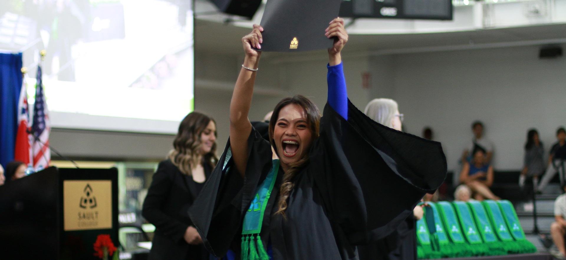 Graduate excited and holding up diploma at convocation