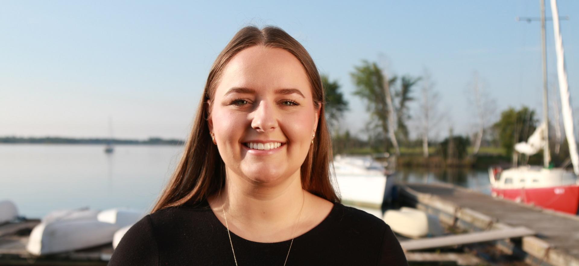 Sienna a graduate of our Bachelor of Science in Nursing program smiling with waterfront in background