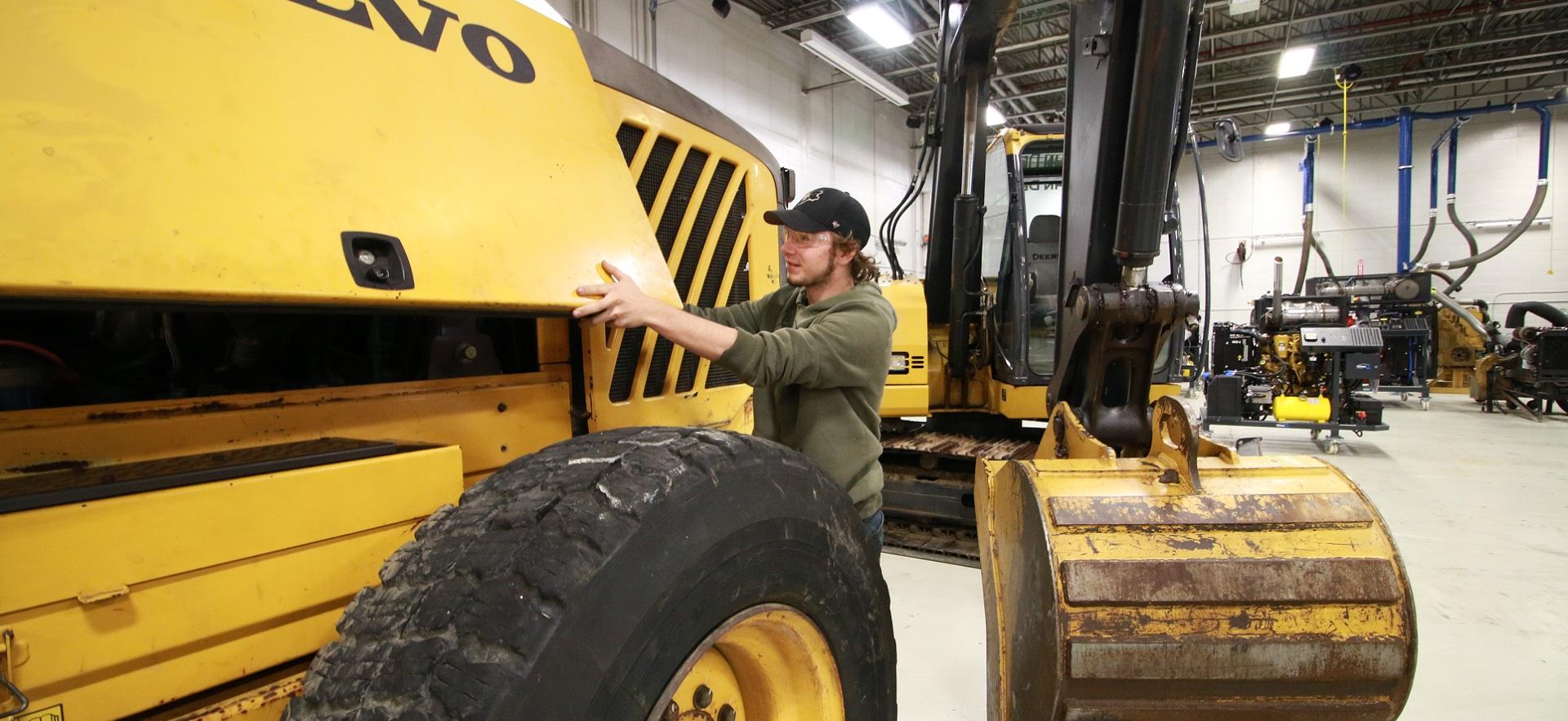 Heavy Equipment student looking under the panel of a tractor