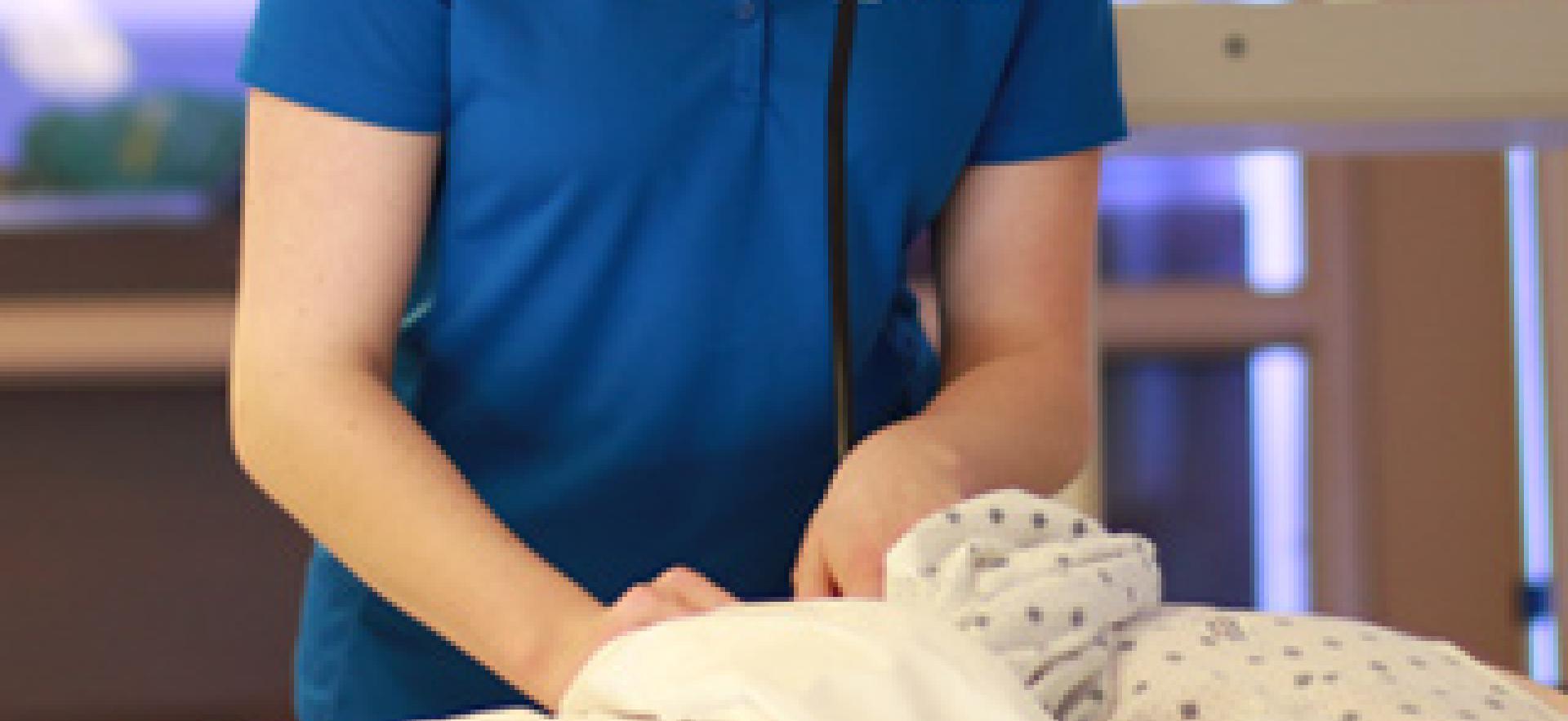 Nursing student with stethoscope assessing mannequin in nursing sim lab