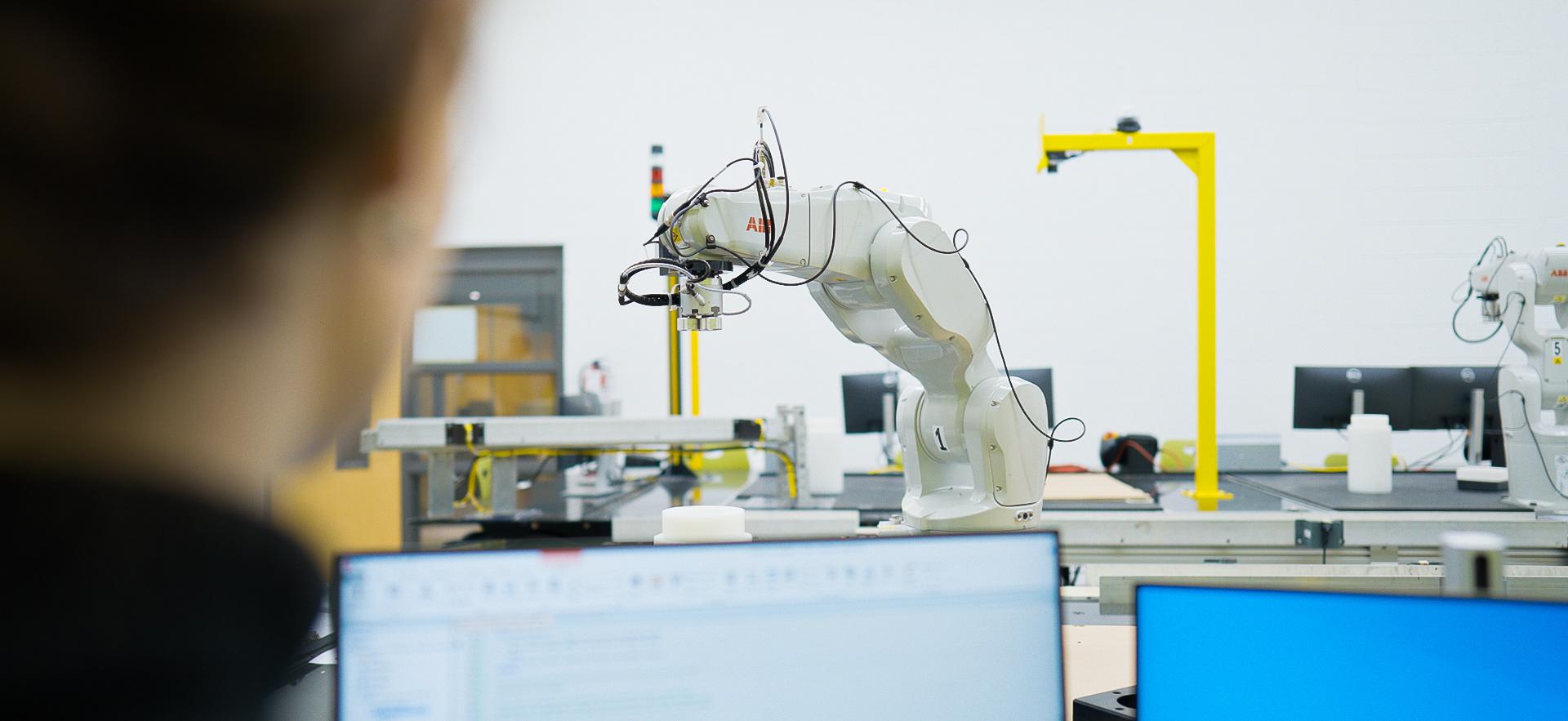 Engineering student controlling a robot arm in the robotics lab