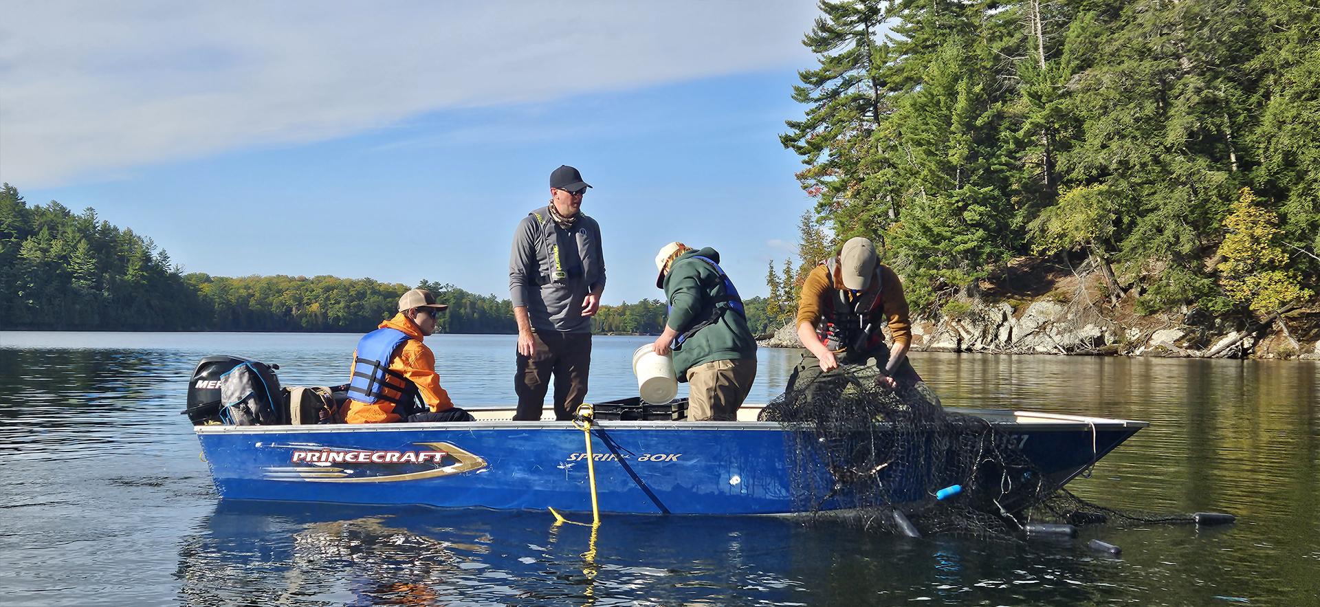 Fish and Wildlife students and faculty fishing on a boat in the lake