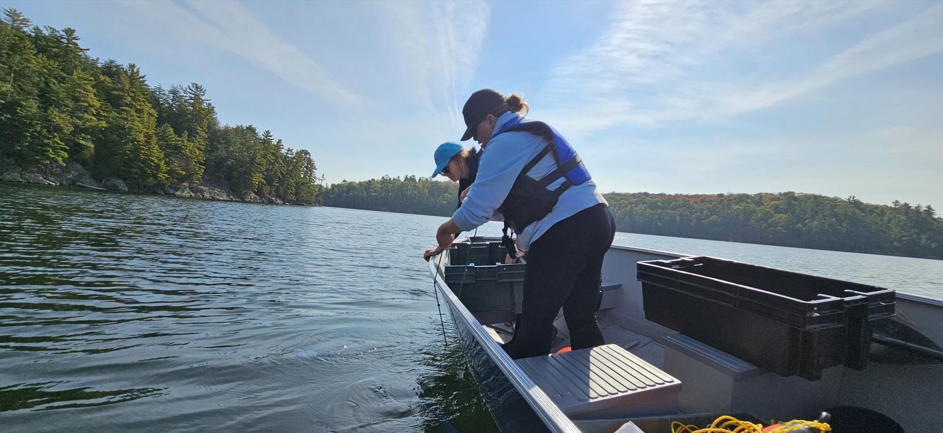 Fish and Wildlife students on a boat casting a net on a lake