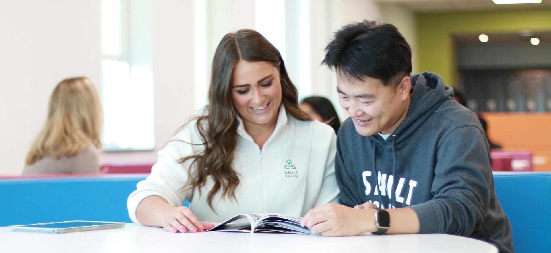Carly student recruiter seated with student looking at program information