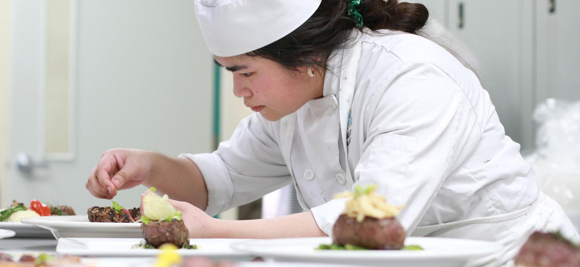 Culinary student plating a disk in the kitchen