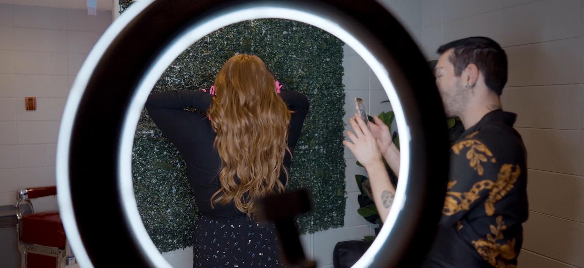 Hairstyling student taking photo of client's hair after styling