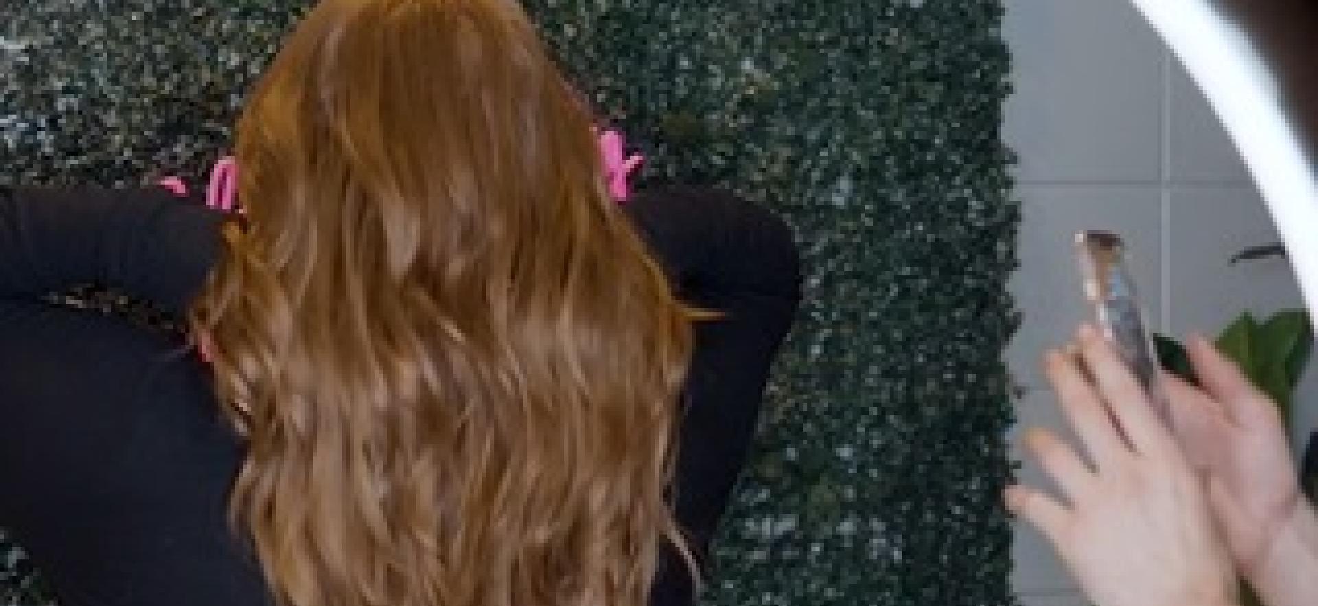 Hairstyling student taking photo of client's hair after styling