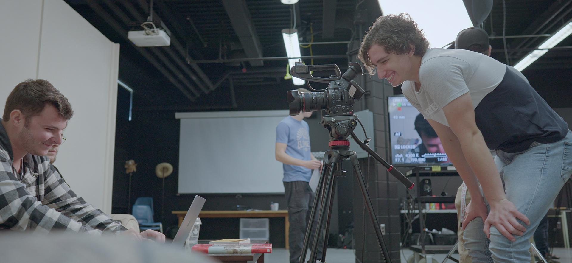 Digital Film student smiling as he films students on the set