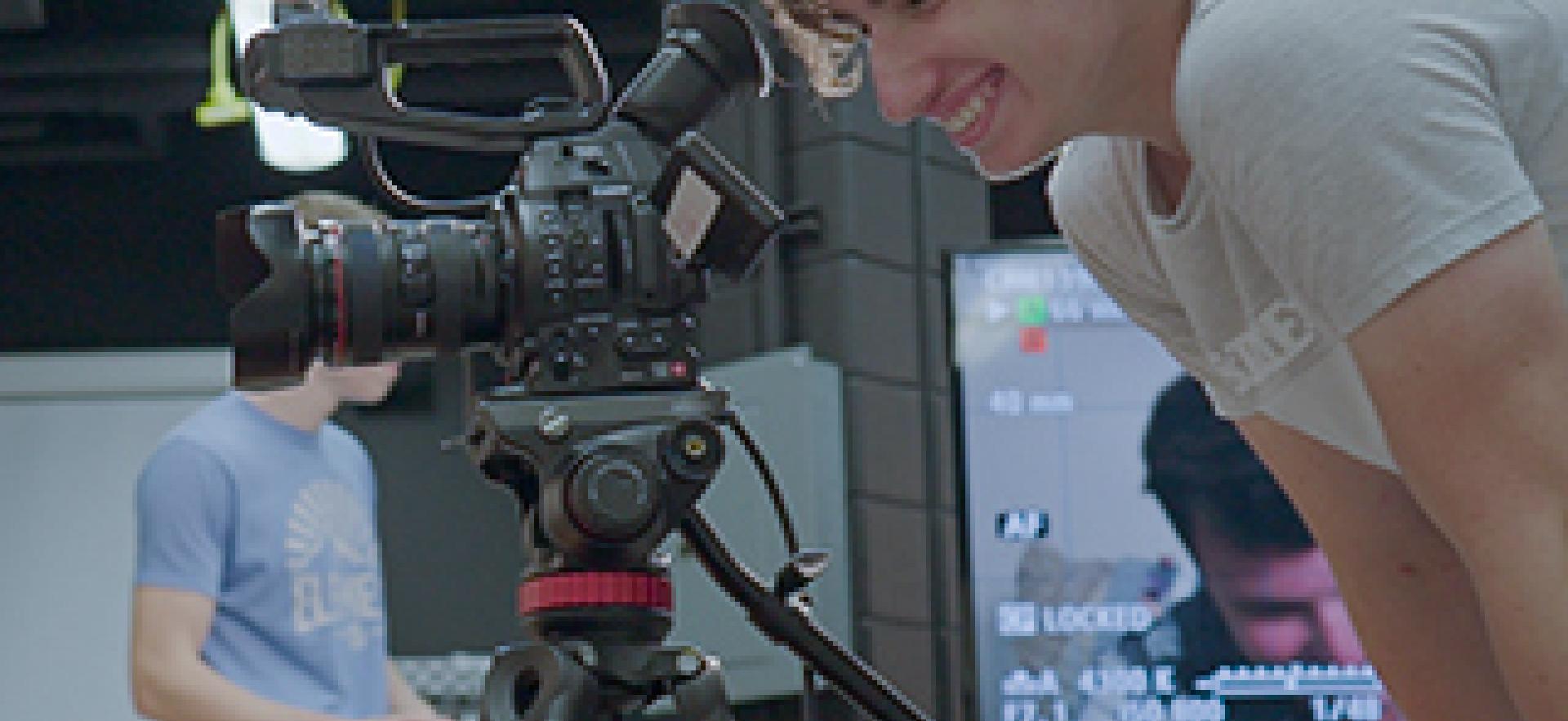 Digital Film student smiling as he films students on the set