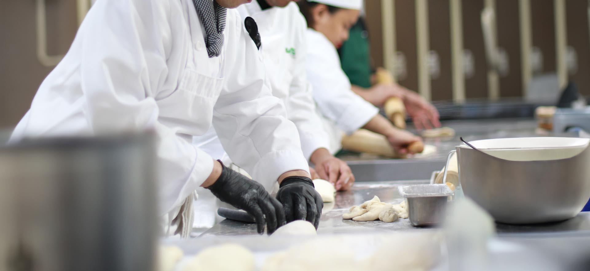 Culinary students shown prepping dough in the kitchen