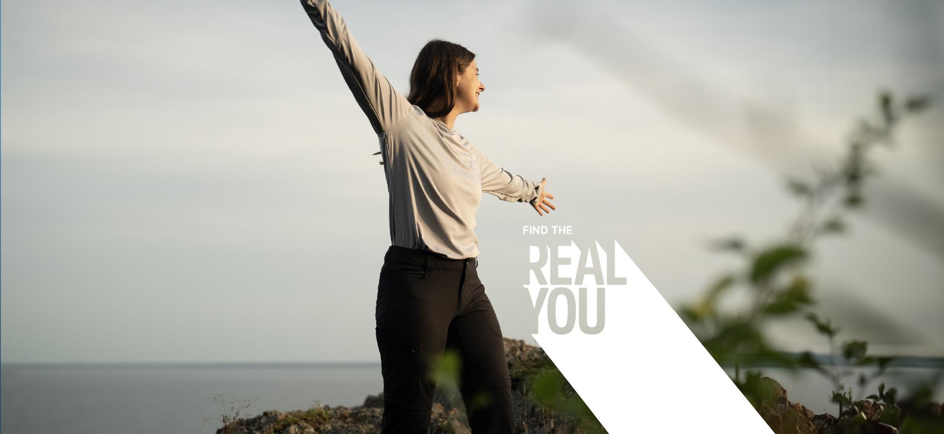 Female student at top of mountain with hands open 