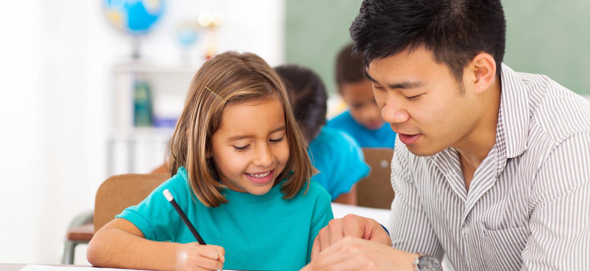 Male educator helping girl with school work