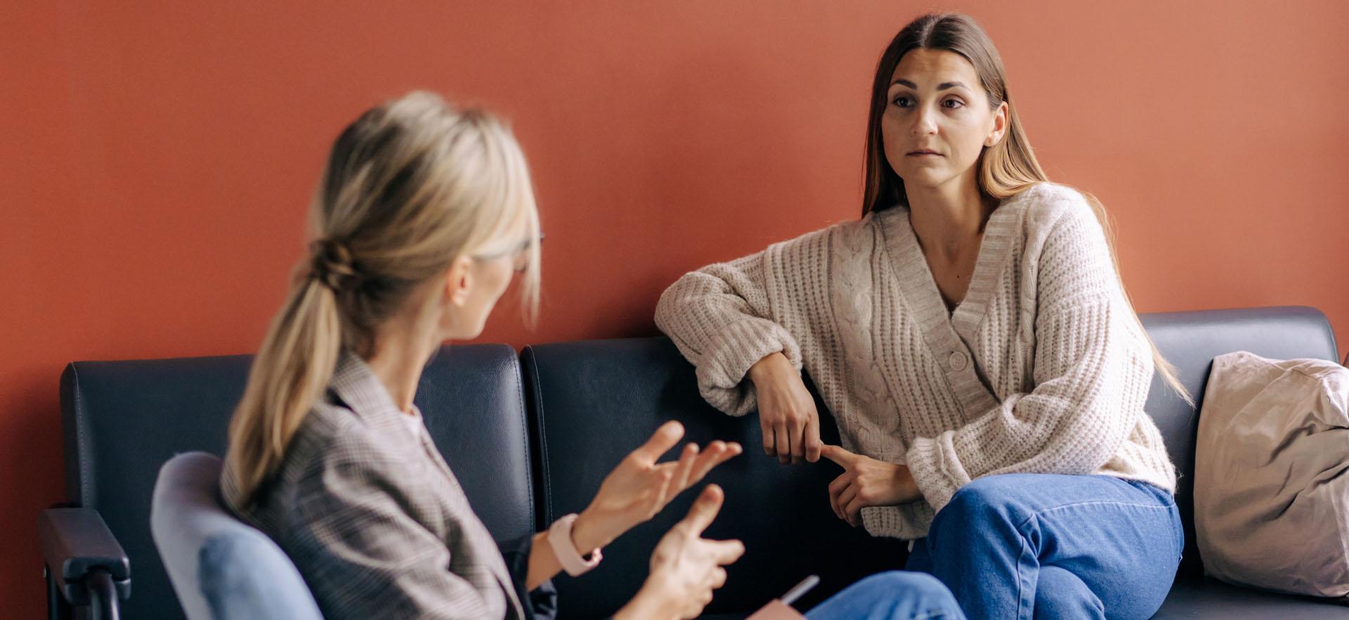 Woman sitting and speaking to someone in a therapy setting