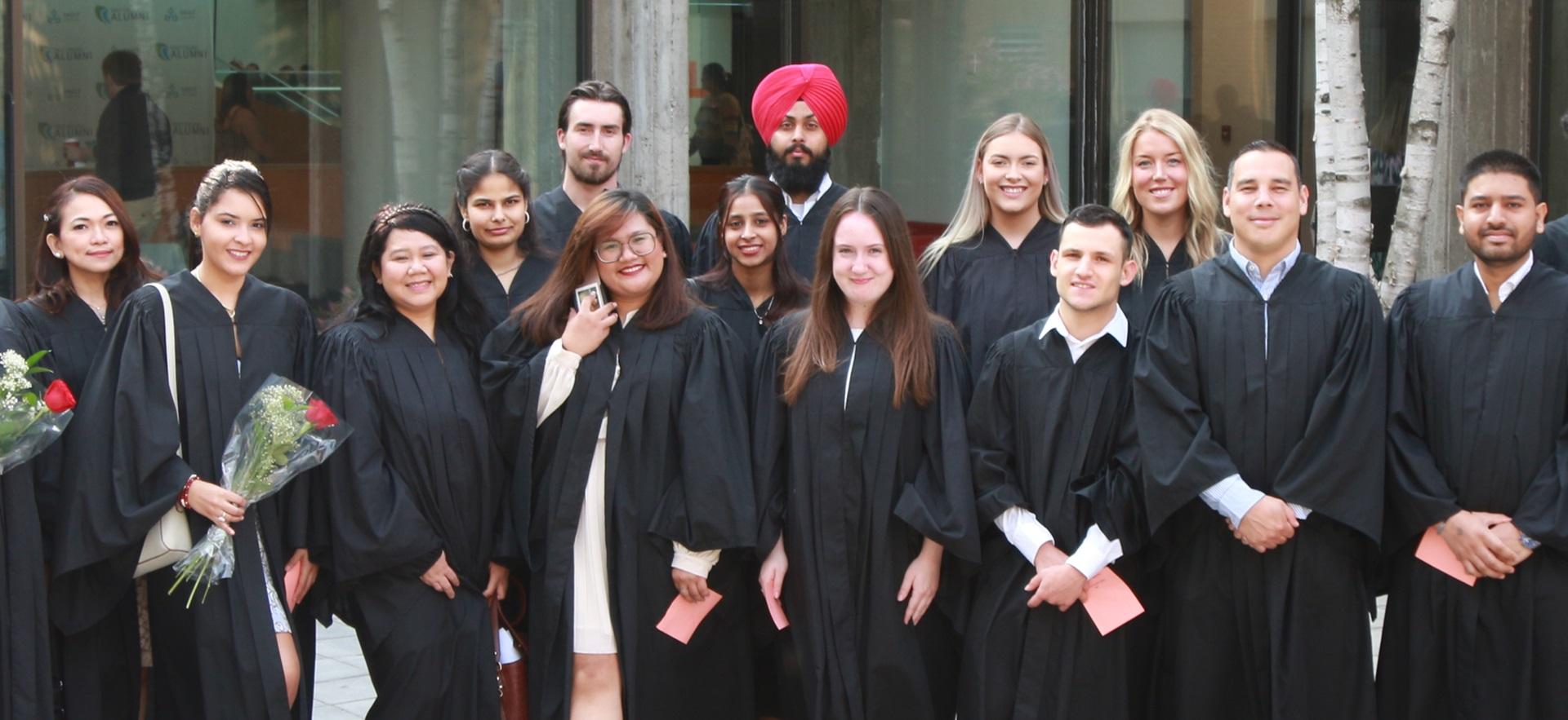 Group of graduates in robes posed together outside for convocation