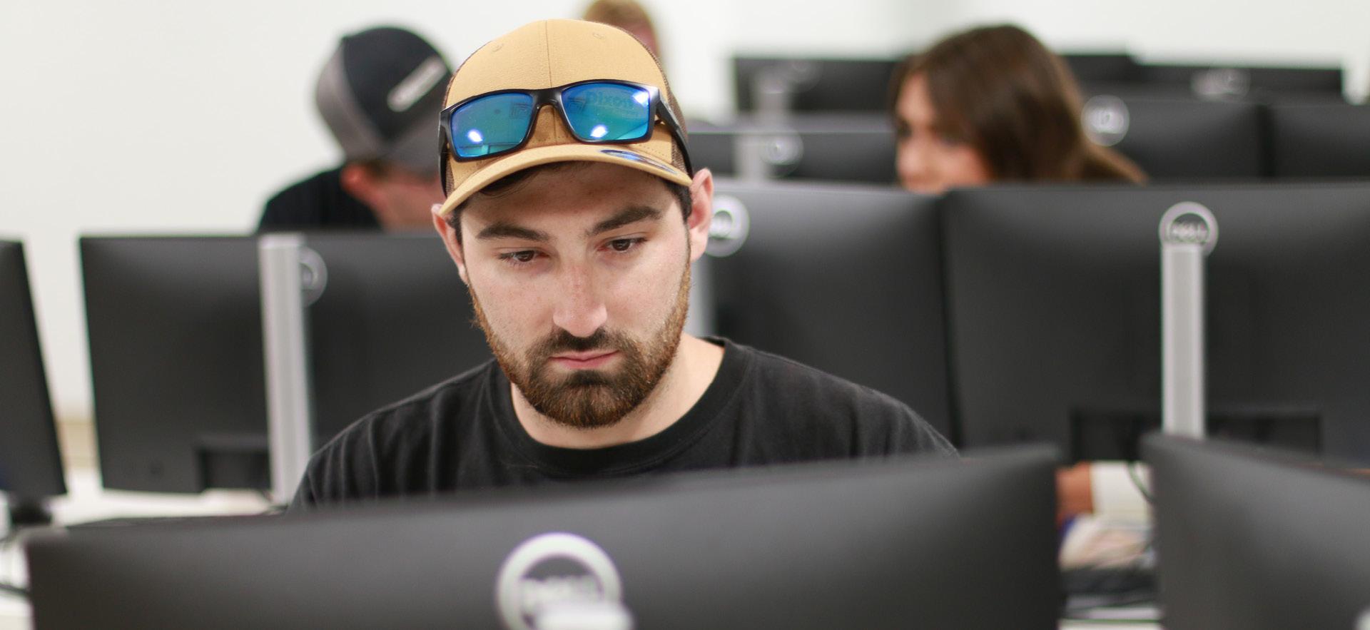 Male student on the computer in a class with students in background