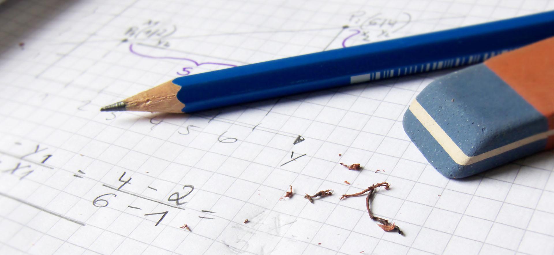 Grid paper shown with equations written and some erasing from pencil and pen on top