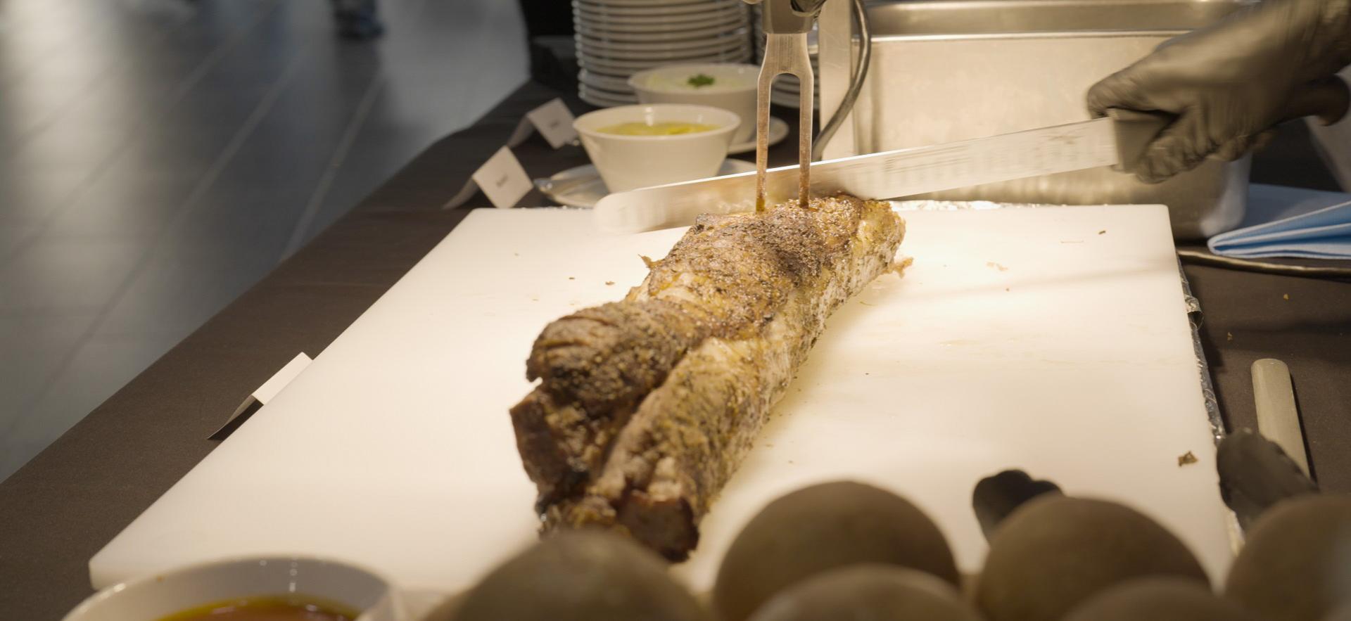 Culinary student slicing meat at carving station at event