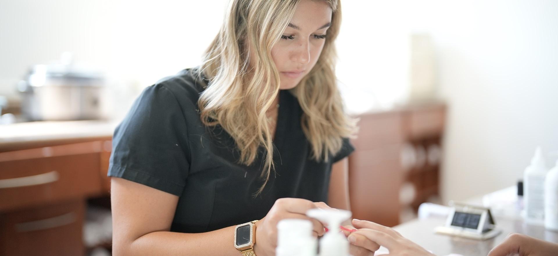 Esthetician student shown applying nail polish