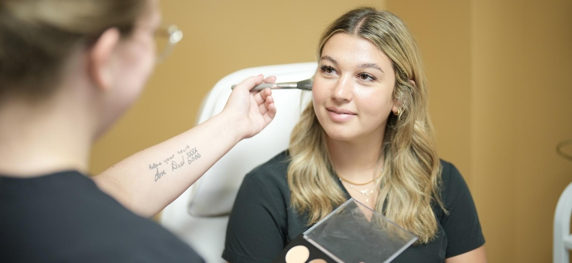 Esthetician student applying makeup to a classmate