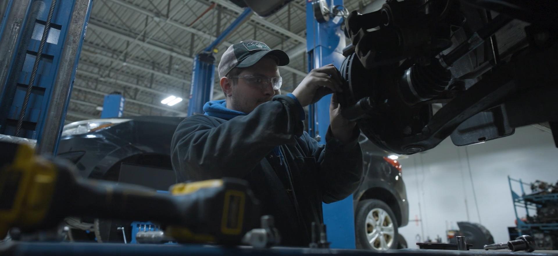 CICE student working on lifted car in motive power centre