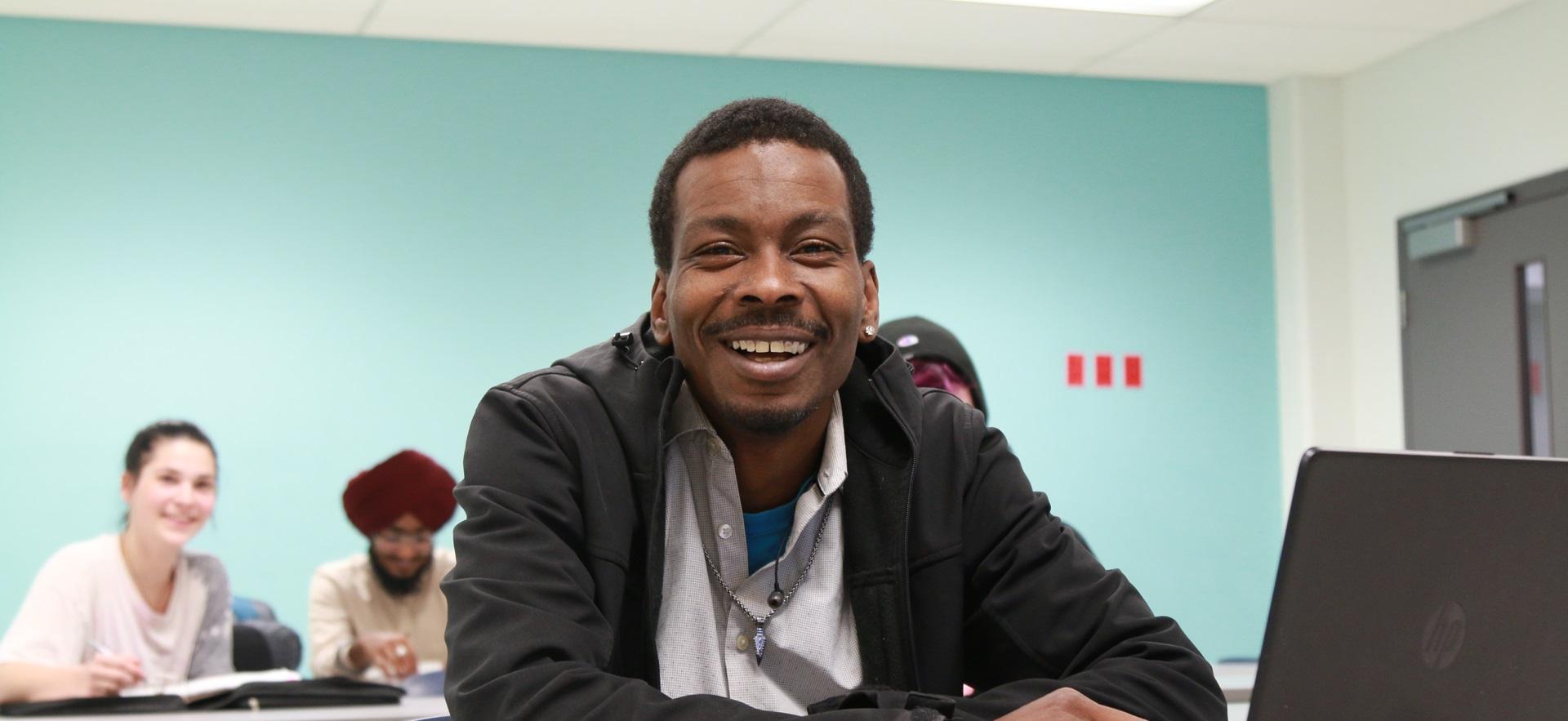 Academic Upgrading student smiling at camera in classroom