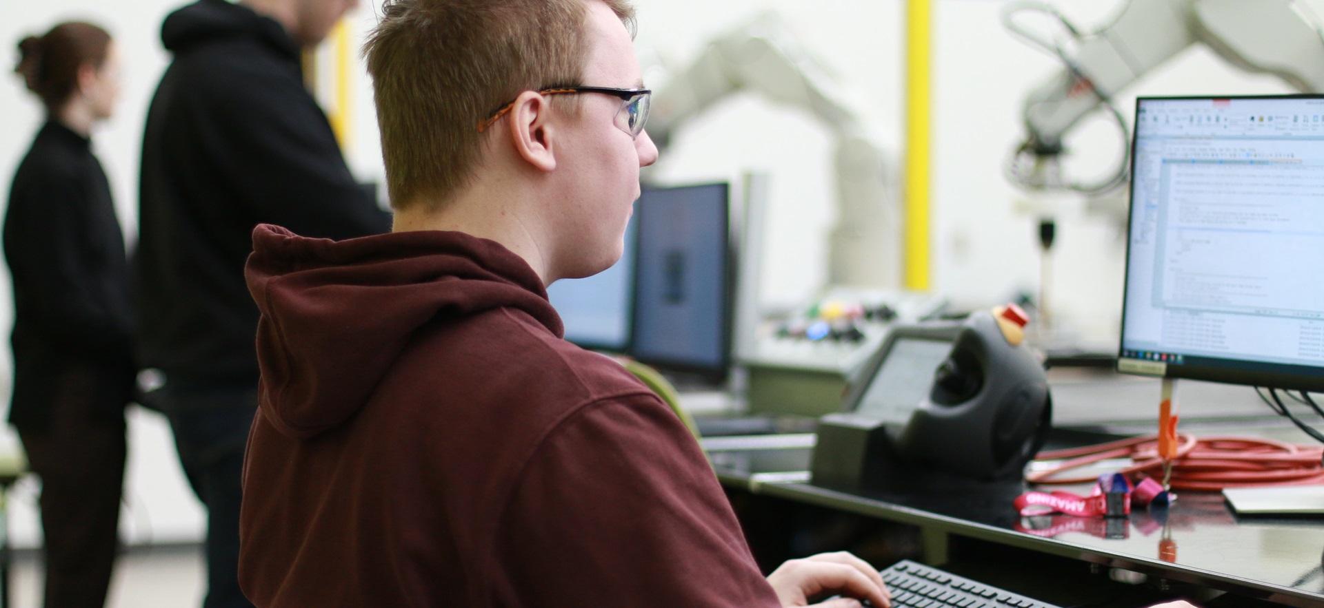 Engineering student working on computer in robotics lab
