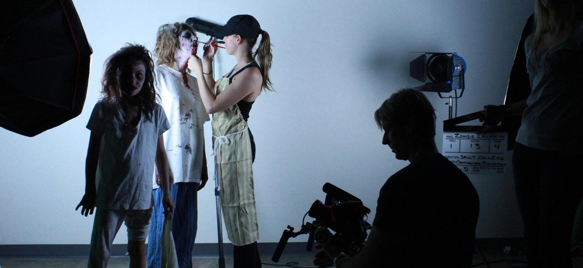 Film students controlling lights, camera and makeup for zombie production