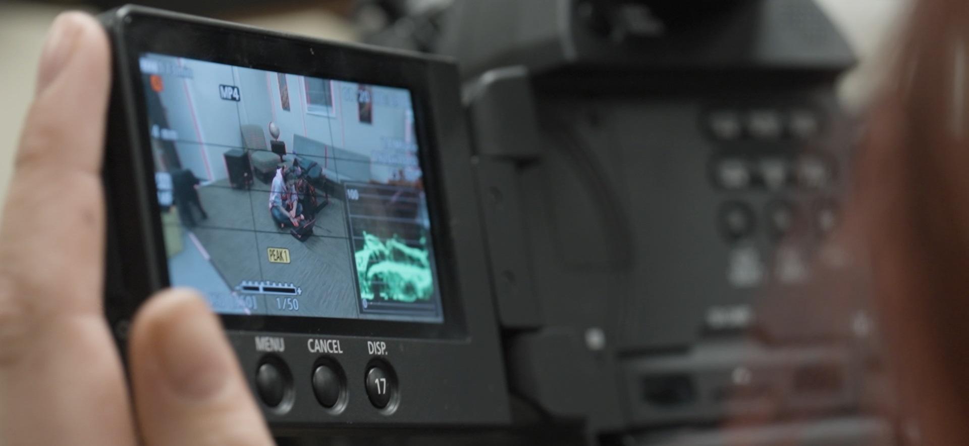 Film student holding camera filming on set
