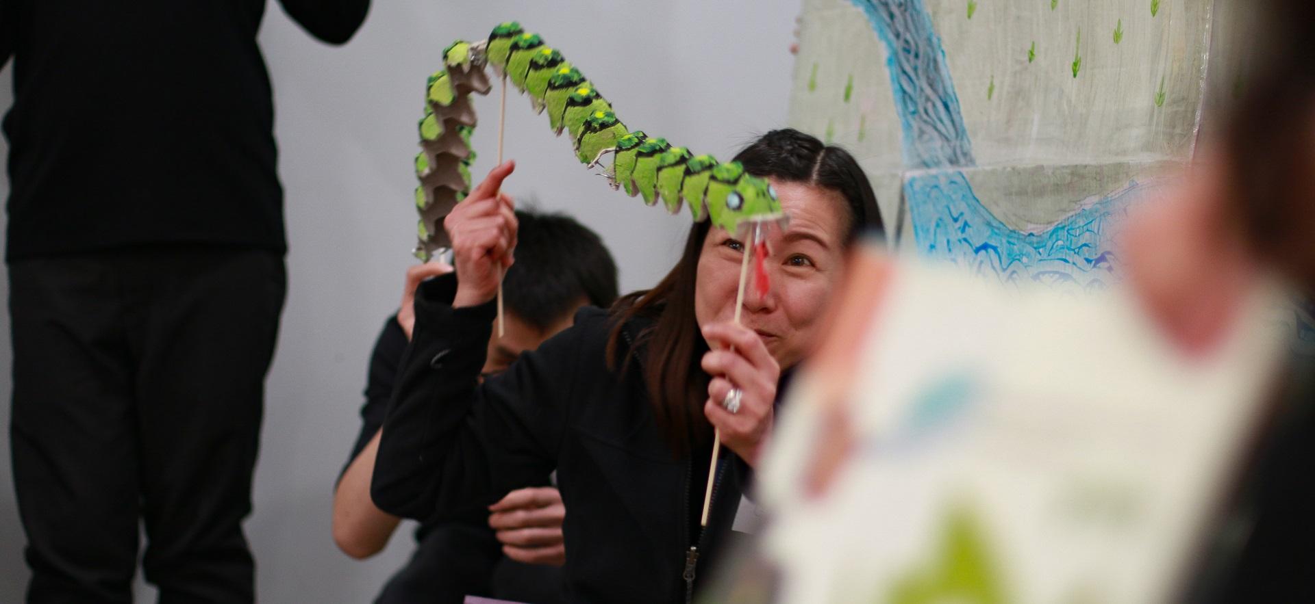 ECE students holding large handmade caterpillar to act out book being read