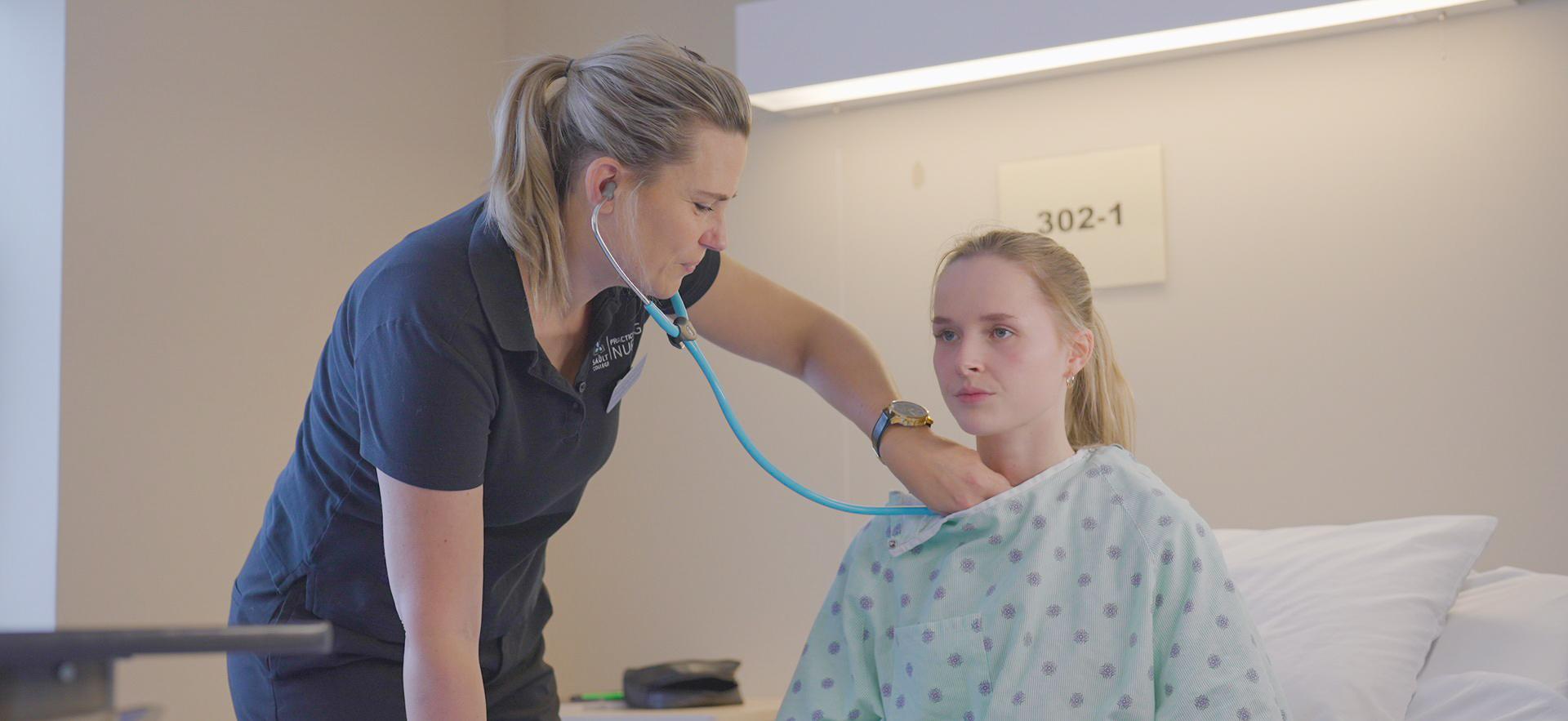 Nursing student checking vitals on classmate posing as patient