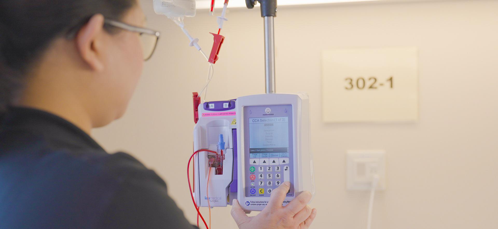 Nursing student turning on machine to start IV