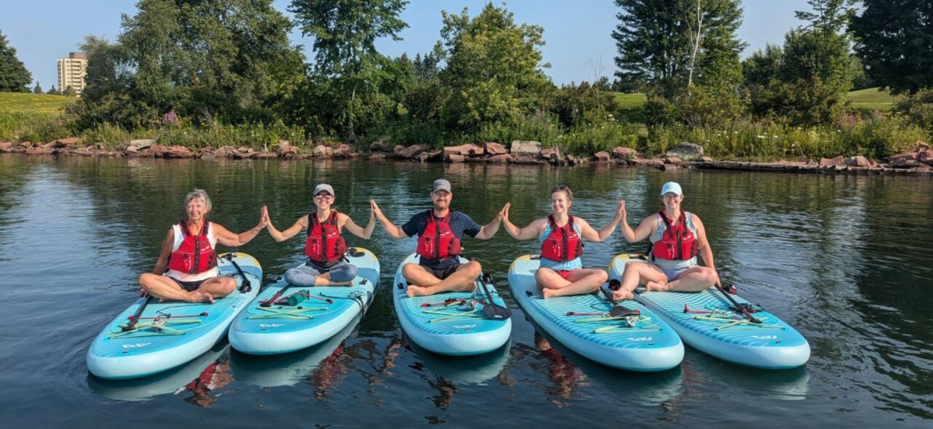 Restore Yoga group sitting on paddleboards on the water