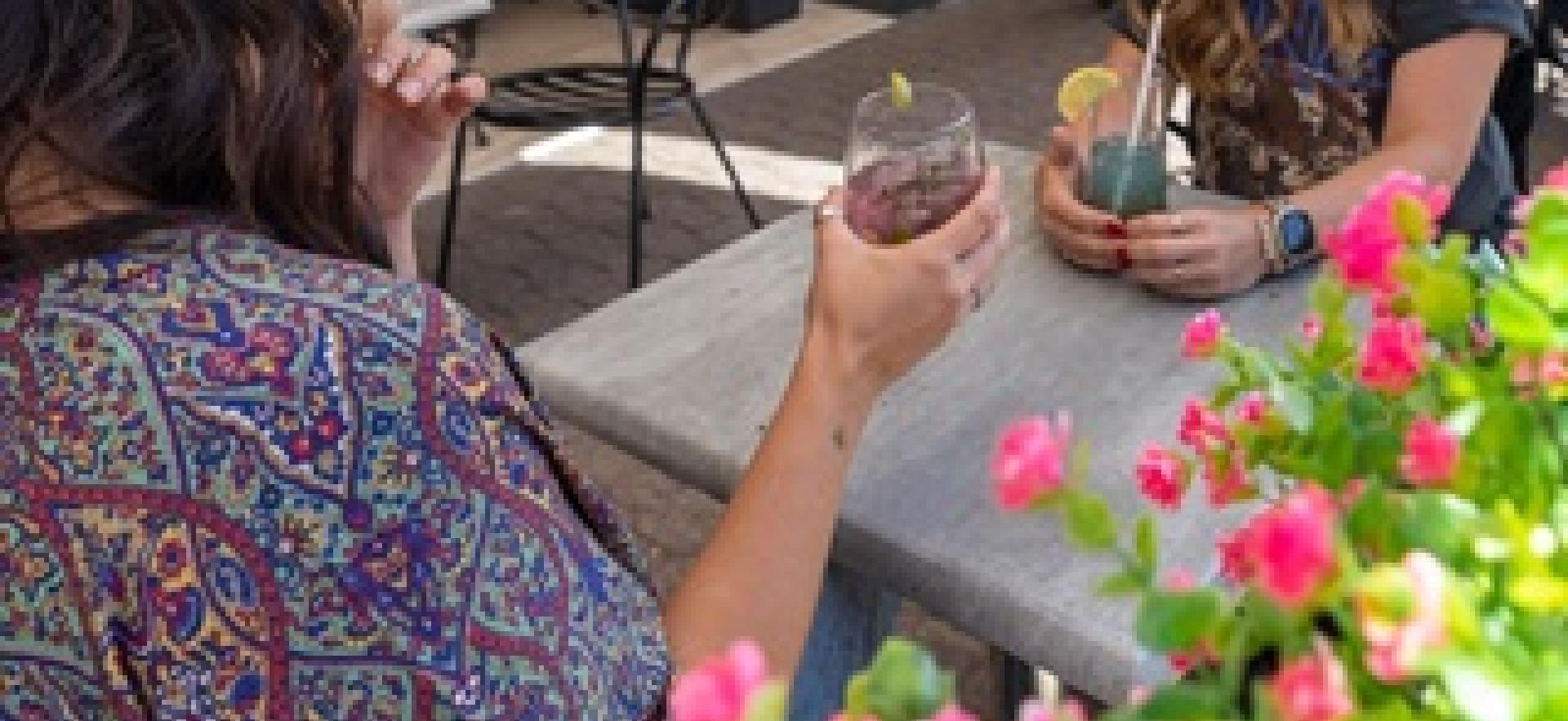 Two women sitting at table talking on downtown patio having a drink