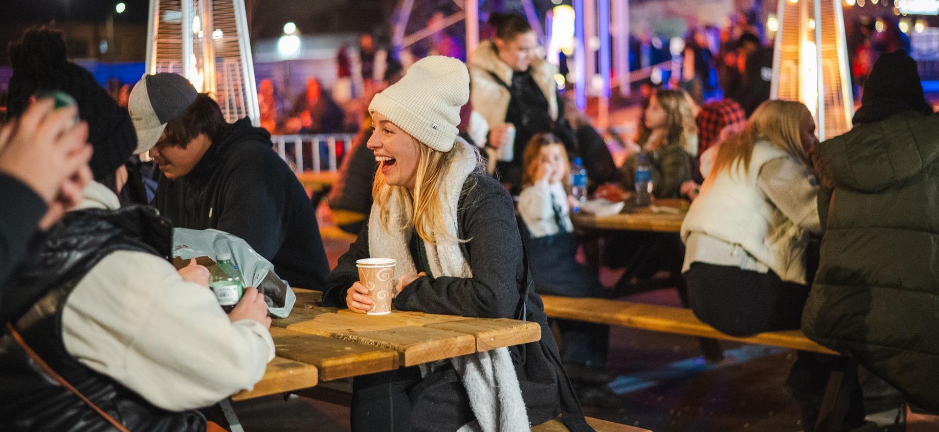 People sitting at tables outside in winter at event