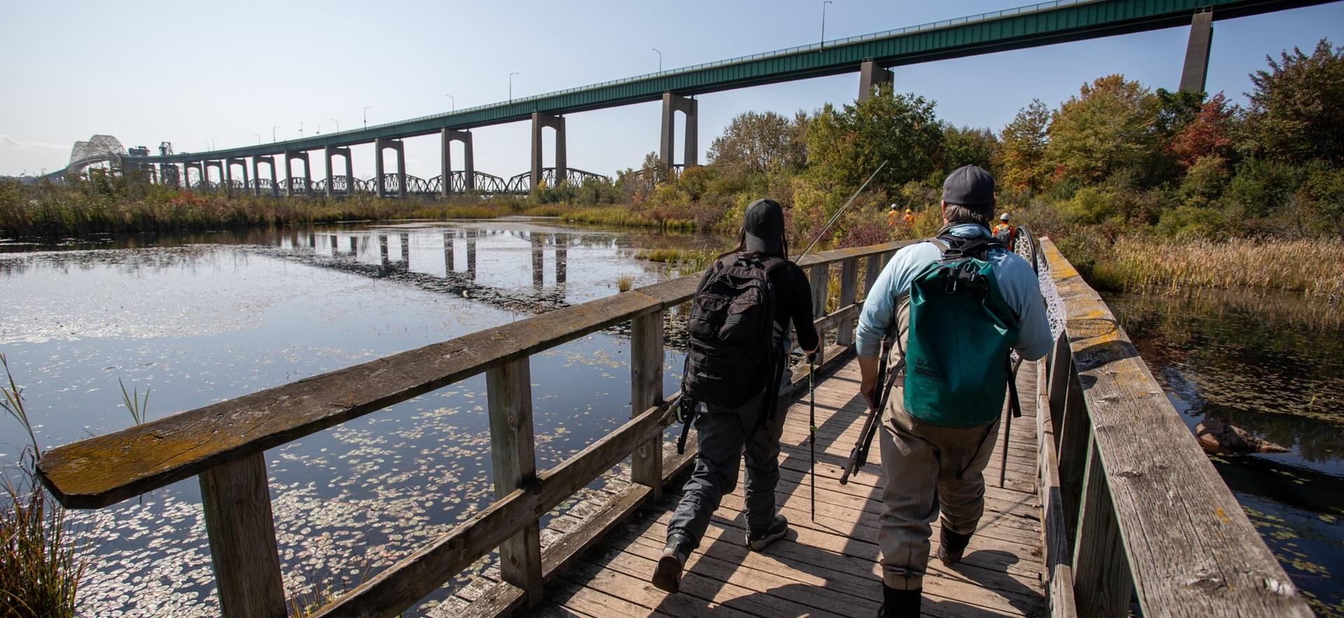 Two men walking along bridge near the Soo Locks with fishing gear