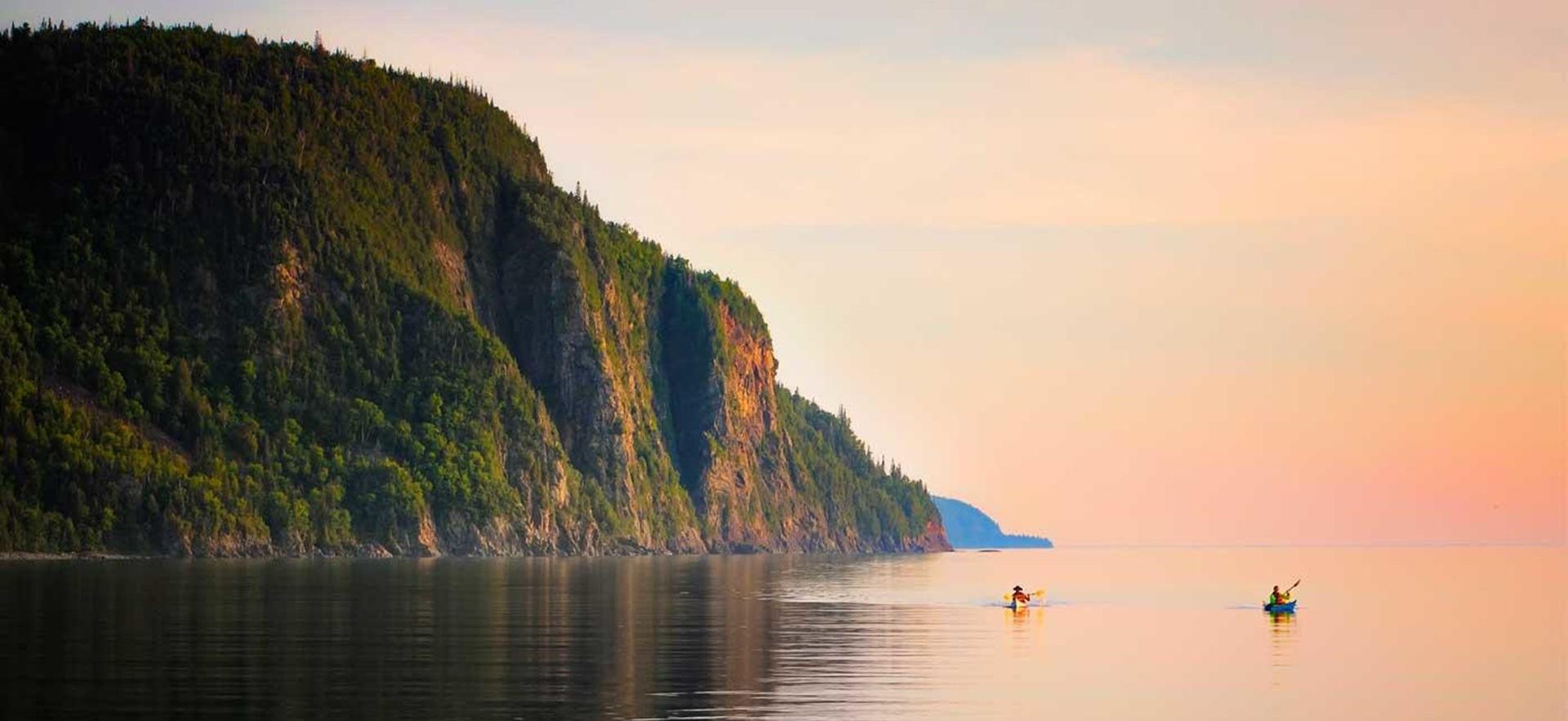 View of a sunset in background and mountain at Old Woman bay with two kayaks on water