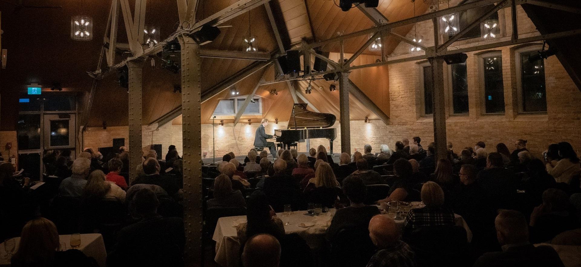 View of musical performance on piano with crowd watching at The Loft