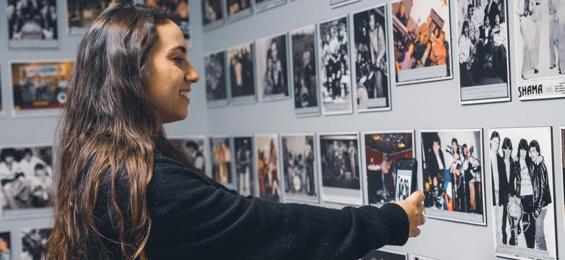 Woman smiling while taking a photo of an image display at the museum