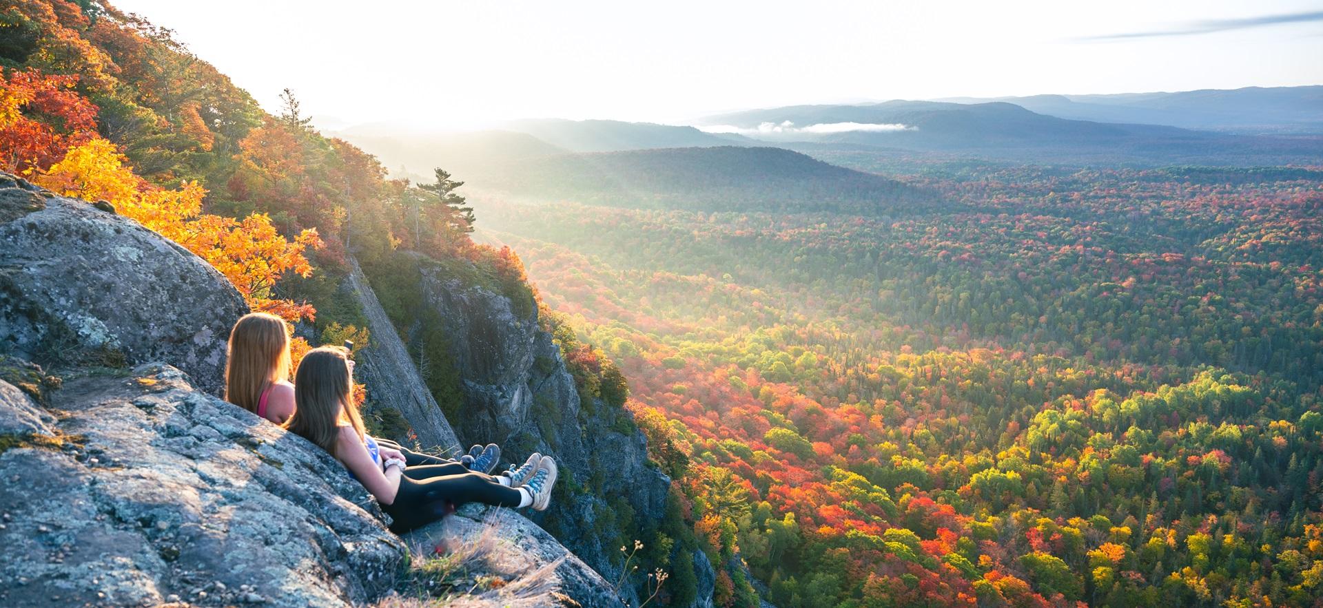Two women sitting on cliff edge overlooking Robertson Cliff in the fall
