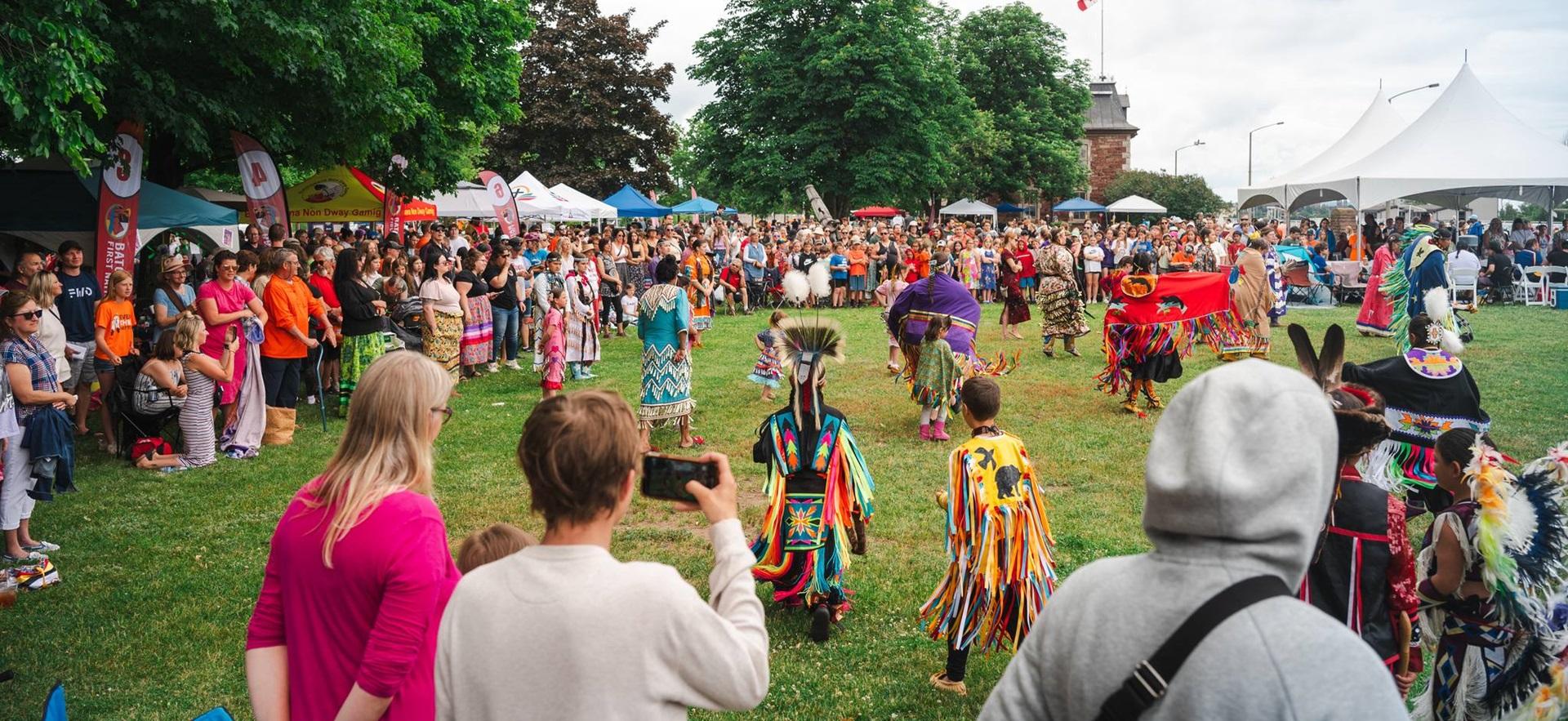 Powwow event outdoors with crowds watching