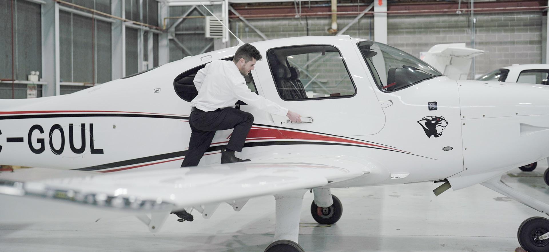 Aviation student stepping onto new Cirrus plane and leaning to open door