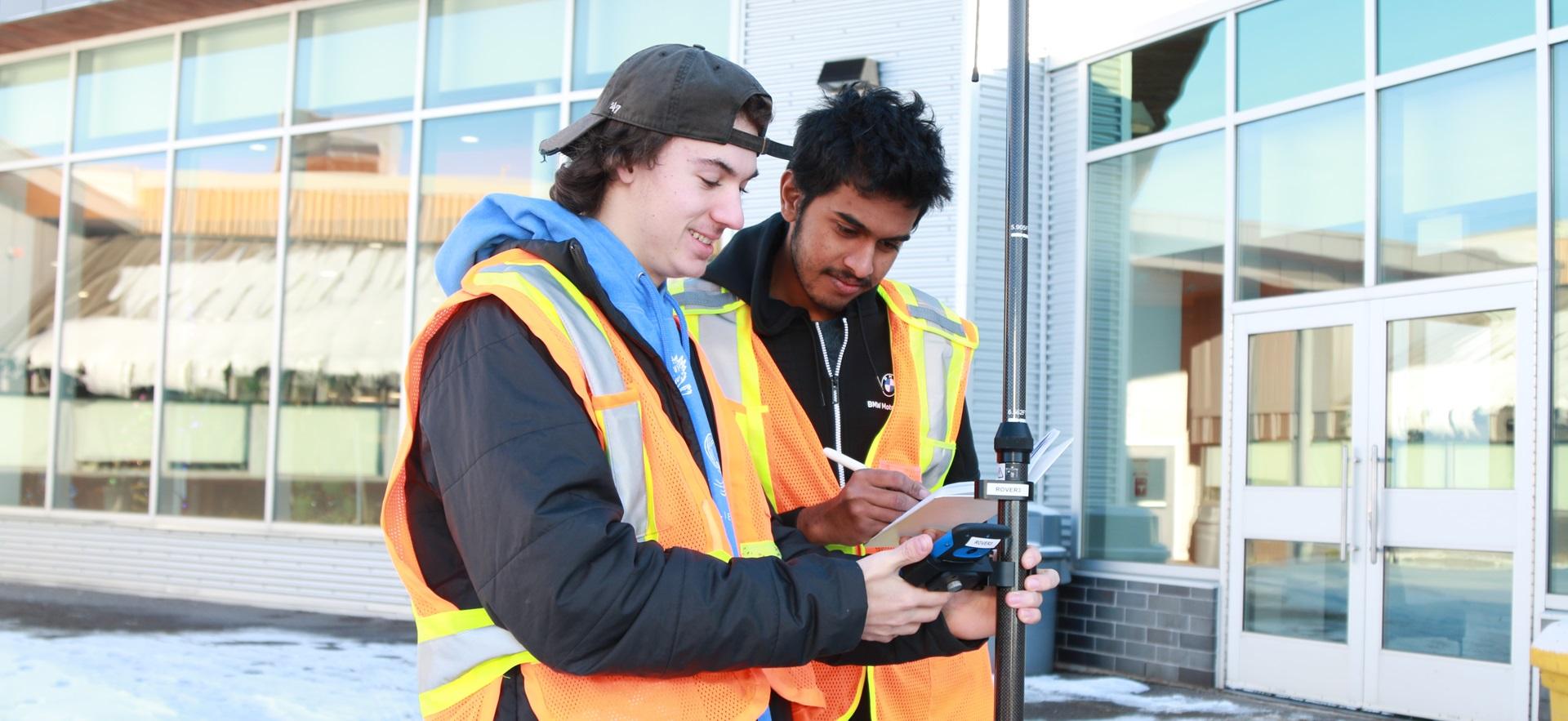 Two Civil Engineering students in safety vests outside in winter