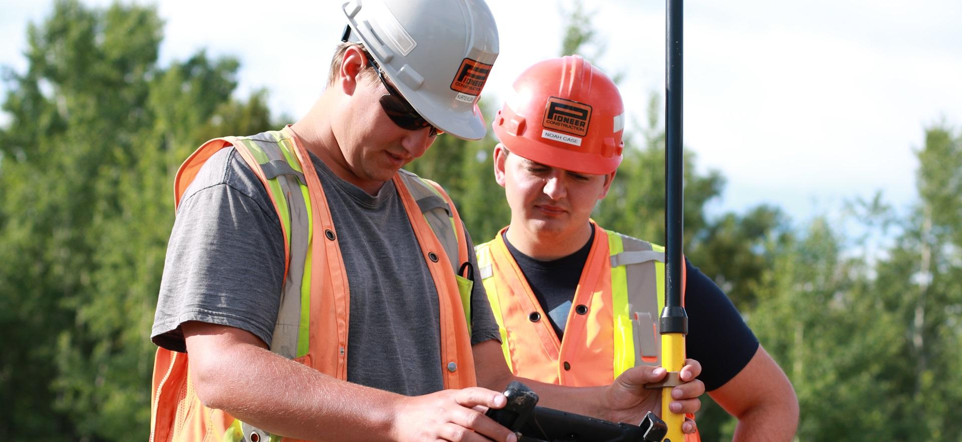 Construction student with employer on construction site with hard hats and equipment