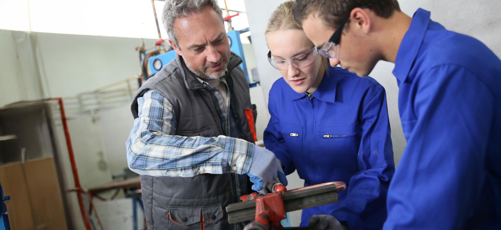 Students listening and working with plumbing instructor