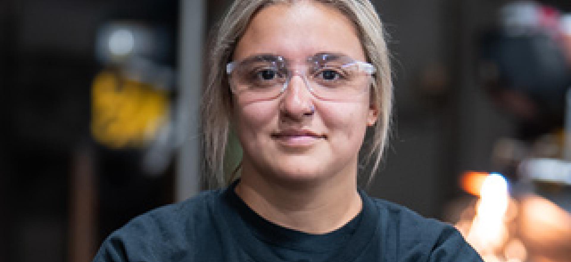 Welding student crossing arms looking at camera in welding shop with Deep Dive text overlay