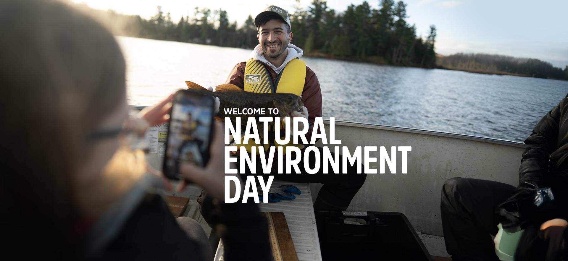 Fish & WIldlife student holding a fish in a boat with Natural Environment Day text overlay