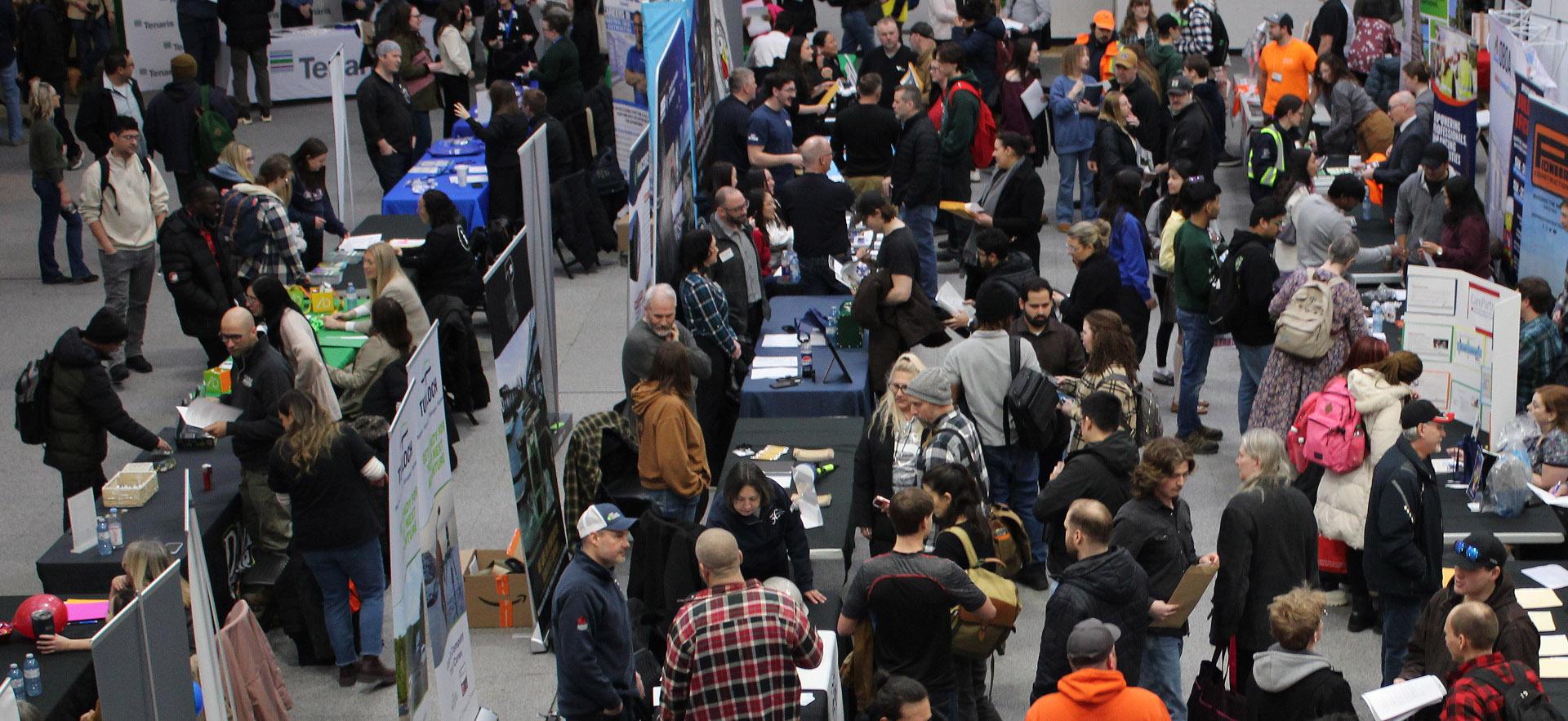 Image of people within a job fair visiting booths 