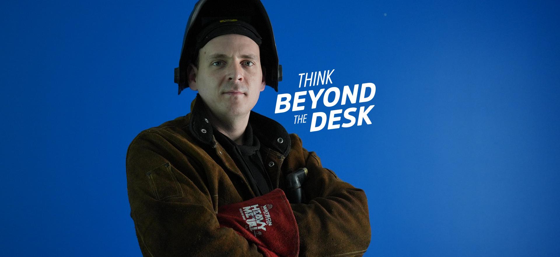 Welding student with arms crossed and welding mask flipped open